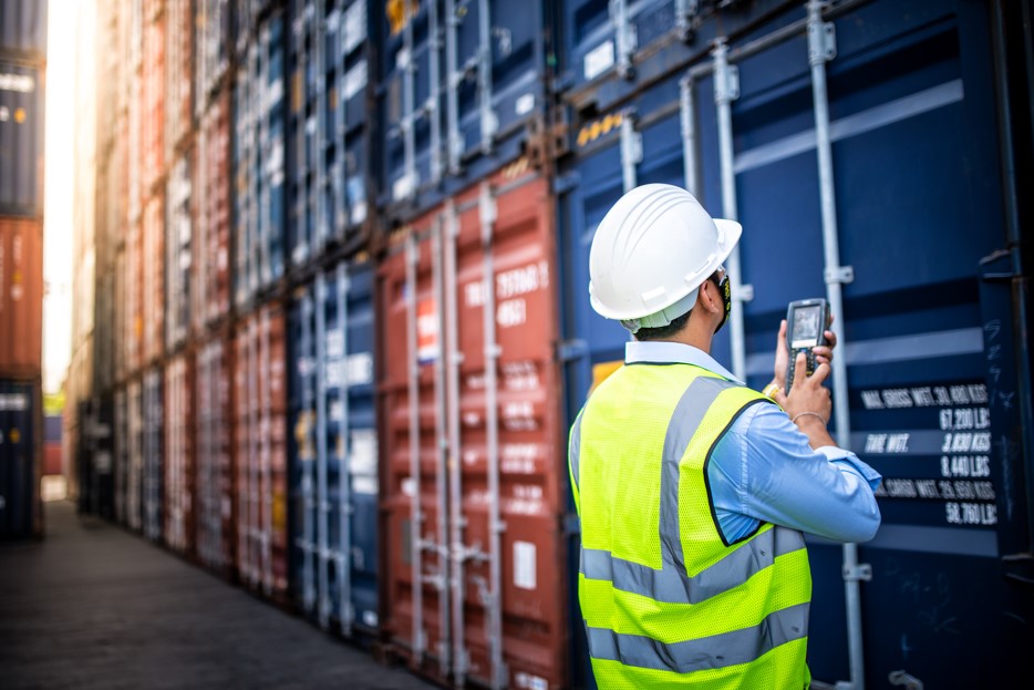 Funcionário de uma empresa de logística em um armazém estudando maneiras de como exportar para Europa.